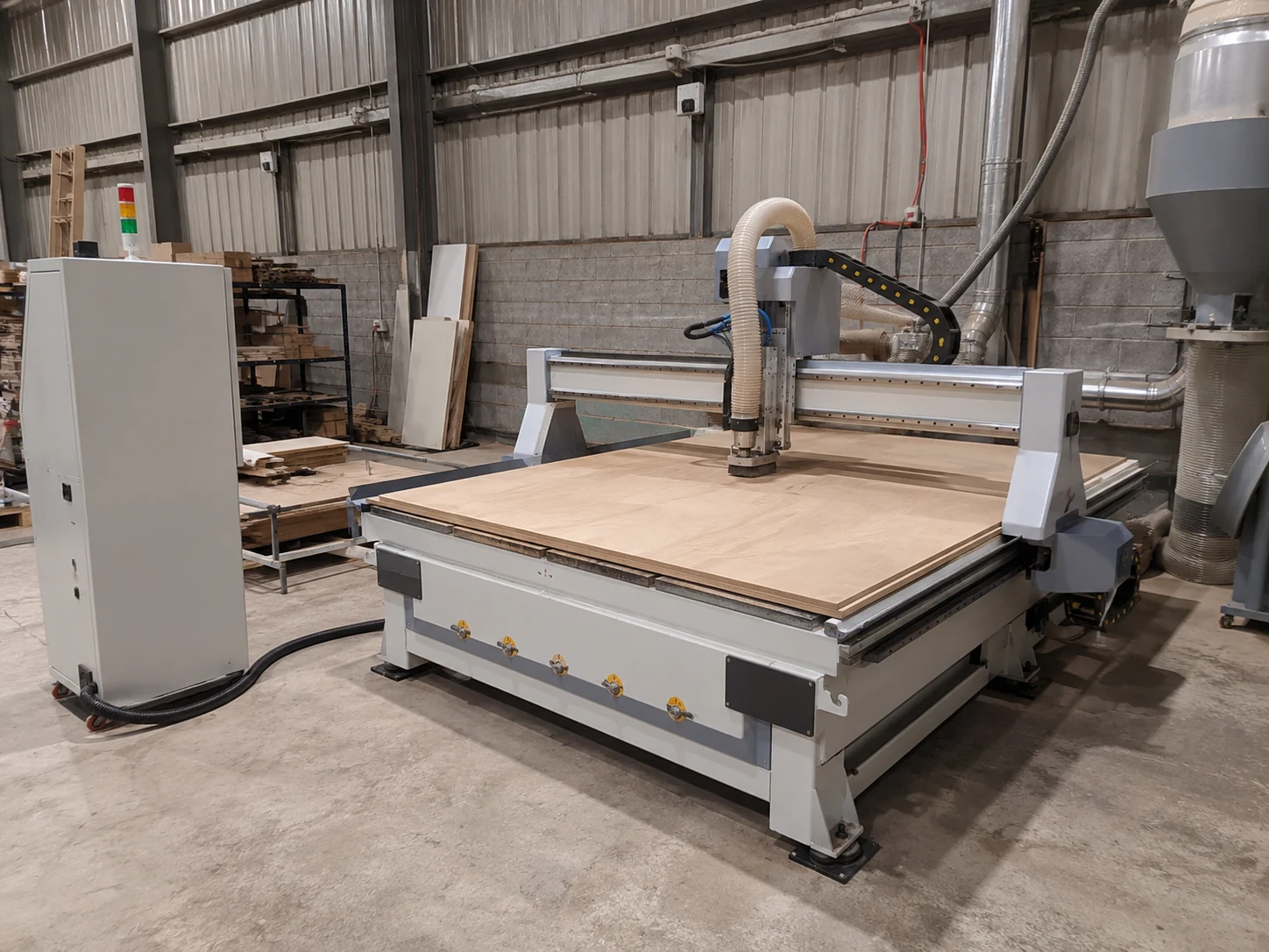 Fraiseuse CNC 3 axes standard usinant un panneau de bois entier dans un atelier de travail du bois
